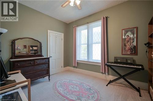 Carpeted room featuring a white paneled door, a multi-pane window with white trim, and a ceiling fan with integrated lighting - 25 Ahrens Street W, Kitchener, ON - Indoor