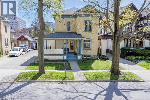 Brick exterior featuring a covered porch, established front lawn, and a paved side driveway - 25 Ahrens Street W, Kitchener, ON - Outdoor With Facade