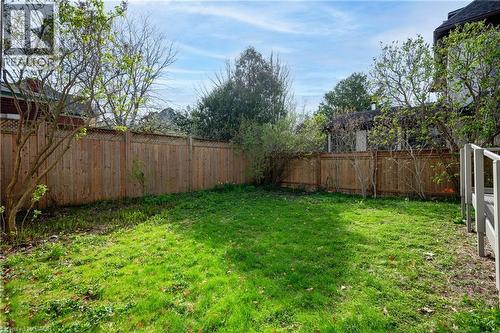 Expansive backyard featuring a lush lawn, privacy fencing, mature trees, and a deck with railings - 25 Ahrens Street W, Kitchener, ON - Outdoor With Backyard