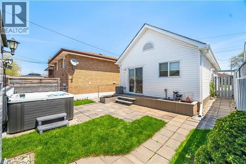 Expansive backyard featuring a hot tub, patio space, and a manicured lawn - 71 Beland Avenue N, Hamilton, ON - Outdoor With Exterior
