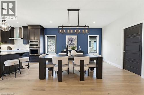 Open-concept dining area featuring a linear chandelier and a striking blue accent wall - 37 Gilmer Crescent, Listowel, ON - Indoor