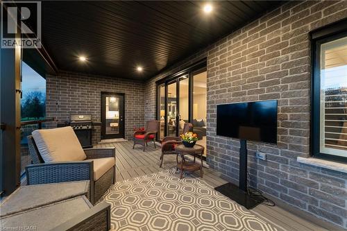 Covered patio featuring a dark slatted ceiling with recessed lighting, brick exterior wall, and composite decking - 37 Gilmer Crescent, Listowel, ON - Outdoor With Deck Patio Veranda With Exterior