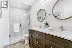 Modern bathroom featuring a double vanity with dark wood-finish cabinetry, white stone countertops, and integrated rectangular sinks - 