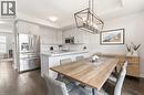 Open-concept kitchen and dining area featuring wood-finish flooring, recessed lighting, white perimeter cabinetry, a center island with countertop seating, and a modern geometric pendant light fixture - 4171 Palermo Common, Burlington, ON  - Indoor 