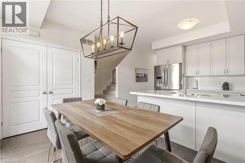 Open-concept dining area featuring a linear chandelier with exposed bulbs - 4171 Palermo Common, Burlington, ON - Indoor
