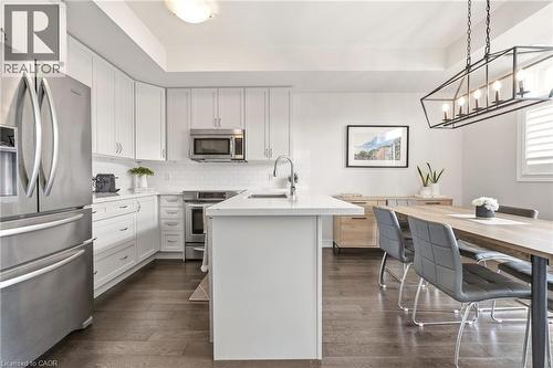 Kitchen featuring white cabinetry, stainless steel appliances, a center island with a sink, white subway tile backsplash, and dark wood-finish flooring - 4171 Palermo Common, Burlington, ON - Indoor Photo Showing Kitchen With Upgraded Kitchen