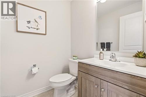 Bathroom featuring a wood-finish vanity with a white countertop, an integrated sink, and a large wall mirror - 4171 Palermo Common, Burlington, ON - Indoor Photo Showing Bathroom