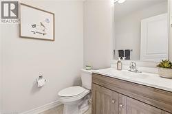 Bathroom featuring a wood-finish vanity with a white countertop, an integrated sink, and a large wall mirror - 