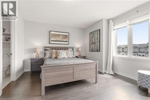 Spacious bedroom featuring dark wood-finish flooring, light-colored walls, and a large window providing natural illumination - 4171 Palermo Common, Burlington, ON - Indoor Photo Showing Bedroom