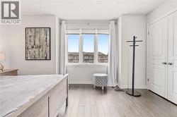 Bright room featuring a large three-panel window, wood-finish flooring, and white baseboards - 