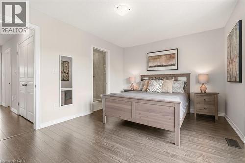 Spacious bedroom featuring wood-finish flooring, light neutral wall tones, and a built-in closet with bifold doors - 4171 Palermo Common, Burlington, ON - Indoor Photo Showing Bedroom