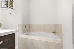 Soaking tub featuring a tiled surround and chrome fixtures - 