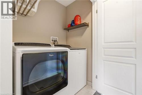 Dedicated laundry area featuring a front-load dryer, top-load washer, wall-mounted drying rack, and a floating wall shelf - 4171 Palermo Common, Burlington, ON - Indoor Photo Showing Laundry Room