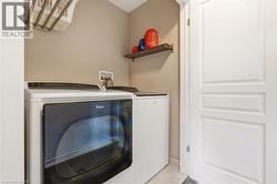 Dedicated laundry area featuring a front-load dryer, top-load washer, wall-mounted drying rack, and a floating wall shelf - 