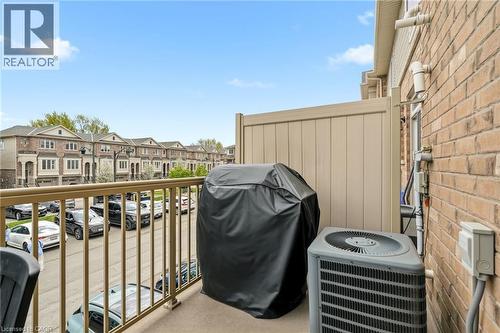 Exterior balcony with a metal railing, brick siding, and a privacy wall - 4171 Palermo Common, Burlington, ON - Outdoor With Exterior