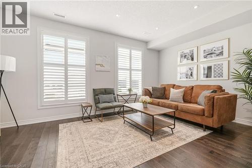 Spacious living area featuring dark wood-finish flooring, recessed lighting, and bright white walls - 4171 Palermo Common, Burlington, ON - Indoor Photo Showing Living Room