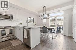 Kitchen featuring white cabinetry, stainless steel appliances, a subway tile backsplash, and light-colored countertops - 