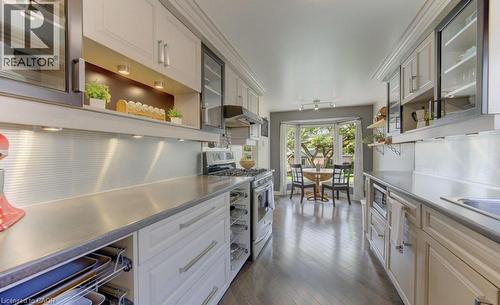 Open-concept kitchen featuring stainless steel countertops, paneled cabinetry, and wood-finish flooring - 108 Clearwater Crescent, Waterloo, ON - Indoor Photo Showing Kitchen