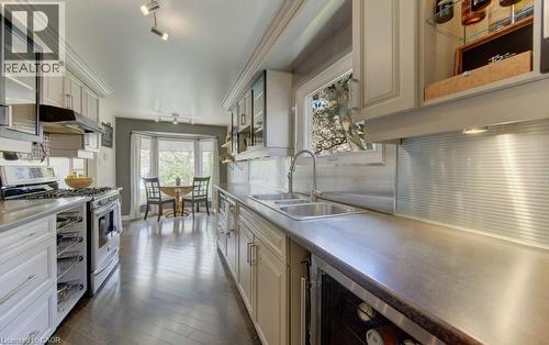 Galley kitchen featuring wood-finish flooring, custom cabinetry, stainless steel appliances, and a double basin sink with a gooseneck faucet - 108 Clearwater Crescent, Waterloo, ON - Indoor Photo Showing Kitchen With Double Sink