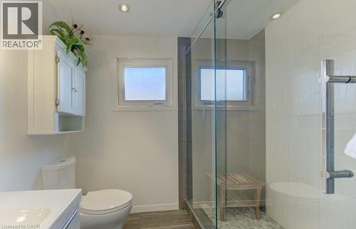 Bathroom featuring a glass-enclosed shower with a built-in bench, a white porcelain toilet, and a wall-mounted medicine cabinet - 108 Clearwater Crescent, Waterloo, ON - Indoor Photo Showing Bathroom