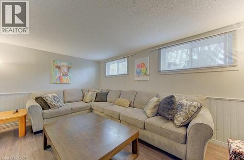 Spacious room featuring wood-finish flooring, light grey walls, and white wainscoting - 108 Clearwater Crescent, Waterloo, ON - Indoor Photo Showing Living Room