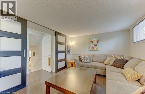 Wood-finish flooring throughout, featuring two sliding panel doors with opaque inserts and brushed metal handles - 108 Clearwater Crescent, Waterloo, ON - Indoor Photo Showing Living Room