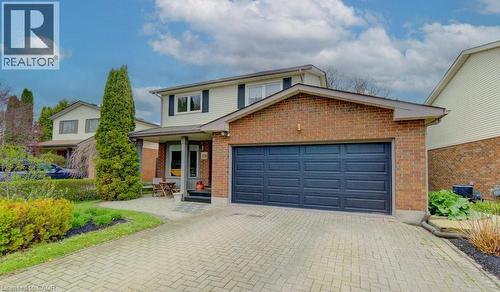 Brick and siding exterior featuring a dark paneled garage door and a herringbone paver driveway - 108 Clearwater Crescent, Waterloo, ON - Outdoor