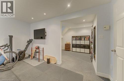Recessed lighting illuminates this versatile space featuring light gray walls, white trim, and a wall-mounted television - 108 Clearwater Crescent, Waterloo, ON - Indoor