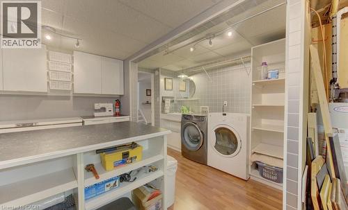 Dedicated utility space featuring track lighting, white cabinetry, a built-in work surface, and wood-finish flooring - 108 Clearwater Crescent, Waterloo, ON - Indoor Photo Showing Laundry Room