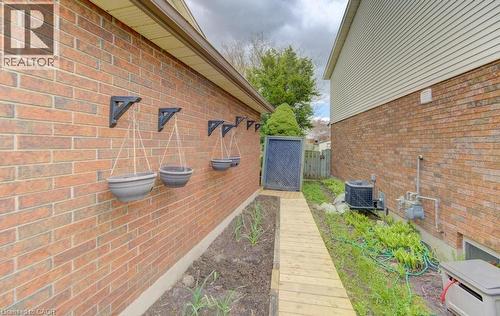 Brick exterior with hanging planter brackets, a garden bed, a wooden walkway, and a rear fence - 108 Clearwater Crescent, Waterloo, ON -  Photo Showing Other Room
