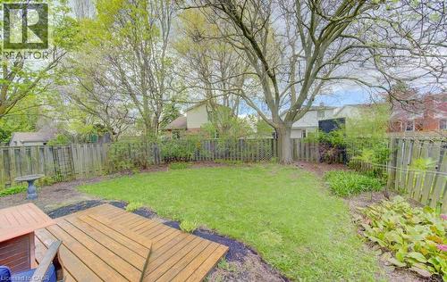 Spacious backyard featuring a wood deck, manicured lawn, mature trees, and a privacy fence - 108 Clearwater Crescent, Waterloo, ON - Outdoor With Backyard