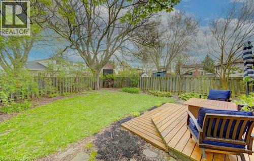 Expansive backyard featuring a wood deck, manicured lawn, and mature trees - 108 Clearwater Crescent, Waterloo, ON - Outdoor