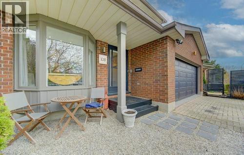 Brick exterior featuring a prominent bay window, attached garage with panel door, stone paver driveway, and a gravel patio area with stepping stones - 108 Clearwater Crescent, Waterloo, ON - Outdoor With Exterior