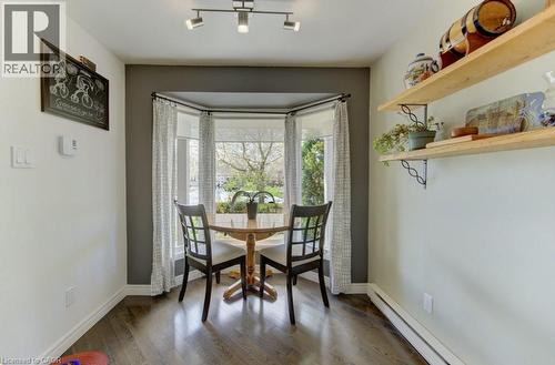 Dining area featuring wood-finish flooring, a bay window with natural light, and a dark accent wall - 108 Clearwater Crescent, Waterloo, ON - Indoor Photo Showing Dining Room