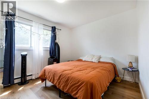 Bright room featuring wood-finish flooring, white walls, and a window with a baseboard heater below - 43 Sixth Avenue, Kitchener, ON - Indoor Photo Showing Bedroom