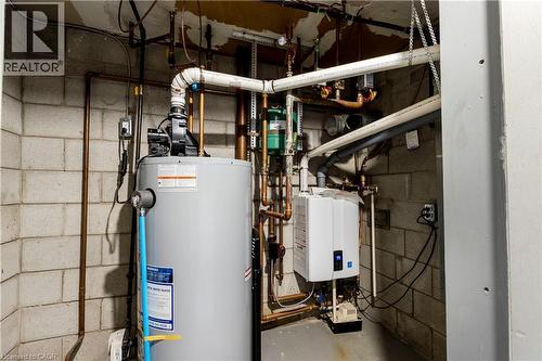 Utility space featuring a tank water heater, a tankless water heater, and extensive copper and PVC plumbing - 43 Sixth Avenue, Kitchener, ON - Indoor Photo Showing Basement