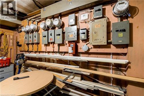 Electrical panels and meters mounted on a wood-paneled wall, featuring exposed conduit and wiring - 43 Sixth Avenue, Kitchener, ON - Indoor