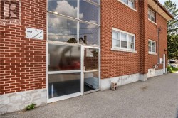 Red brick exterior with multiple windows, a glass-paneled entrance, and a concrete foundation - 