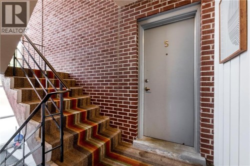 Brick wall detailing with a gray entry door, brass-finish door number, and a secure lockset - 43 Sixth Avenue, Kitchener, ON -  With Exterior