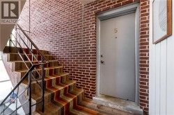 Brick wall detailing with a gray entry door, brass-finish door number, and a secure lockset - 