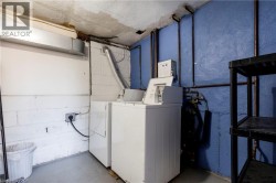 Laundry area featuring white block walls, concrete flooring, exposed utility piping, and a washer and dryer set - 