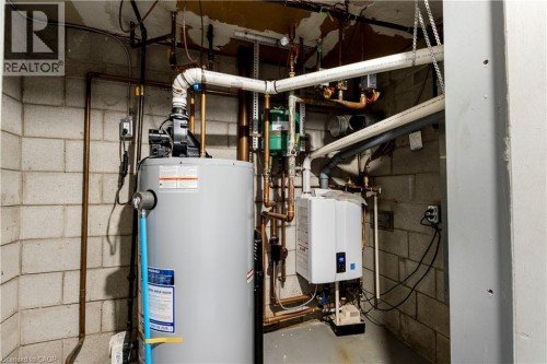 Utility space featuring a tank water heater, a tankless water heater, and extensive copper and PVC plumbing - 43 Sixth Avenue, Kitchener, ON - Indoor Photo Showing Basement