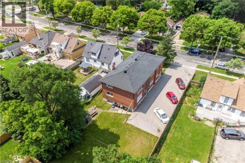 Brick multi-unit building featuring a dark shingled roof, a paved parking area, and mature perimeter trees - 43 Sixth Avenue, Kitchener, ON - Outdoor With View