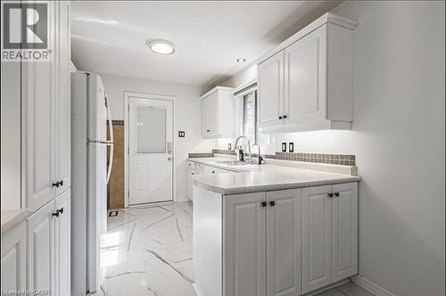 Kitchen with white cabinets, light countertops, freestanding refrigerator, light marble finish floors, and a peninsula - 267 Erb Street E, Waterloo, ON - Indoor