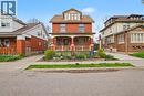 Red brick facade residence featuring a covered front porch with decorative railing, dormer window, and a planted front garden bed - 30 Hohner Avenue, Kitchener, ON  - Outdoor 