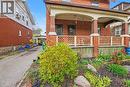 Brick facade featuring a covered front porch with arched details and decorative lattice railing - 30 Hohner Avenue, Kitchener, ON  - Outdoor With Deck Patio Veranda 