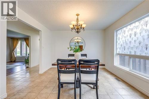 Dining area featuring tiled flooring, a decorative chandelier, and a large window with patterned privacy film - 43 Niska Drive, Waterdown, ON - Indoor Photo Showing Dining Room