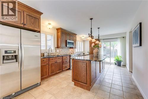Kitchen featuring wood cabinetry, stainless steel appliances, a center island with a dark countertop, tile flooring, and a sliding glass door to the exterior - 43 Niska Drive, Waterdown, ON - Indoor Photo Showing Kitchen With Stainless Steel Kitchen