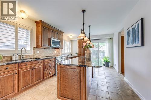 Kitchen featuring wood cabinetry, dark granite countertops, stainless steel appliances, and a mosaic tile backsplash - 43 Niska Drive, Waterdown, ON - Indoor Photo Showing Kitchen