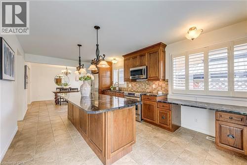 Spacious kitchen featuring an expansive center island with dark countertops, wood cabinetry, stainless steel appliances, and a mosaic tile backsplash - 43 Niska Drive, Waterdown, ON - Indoor Photo Showing Kitchen